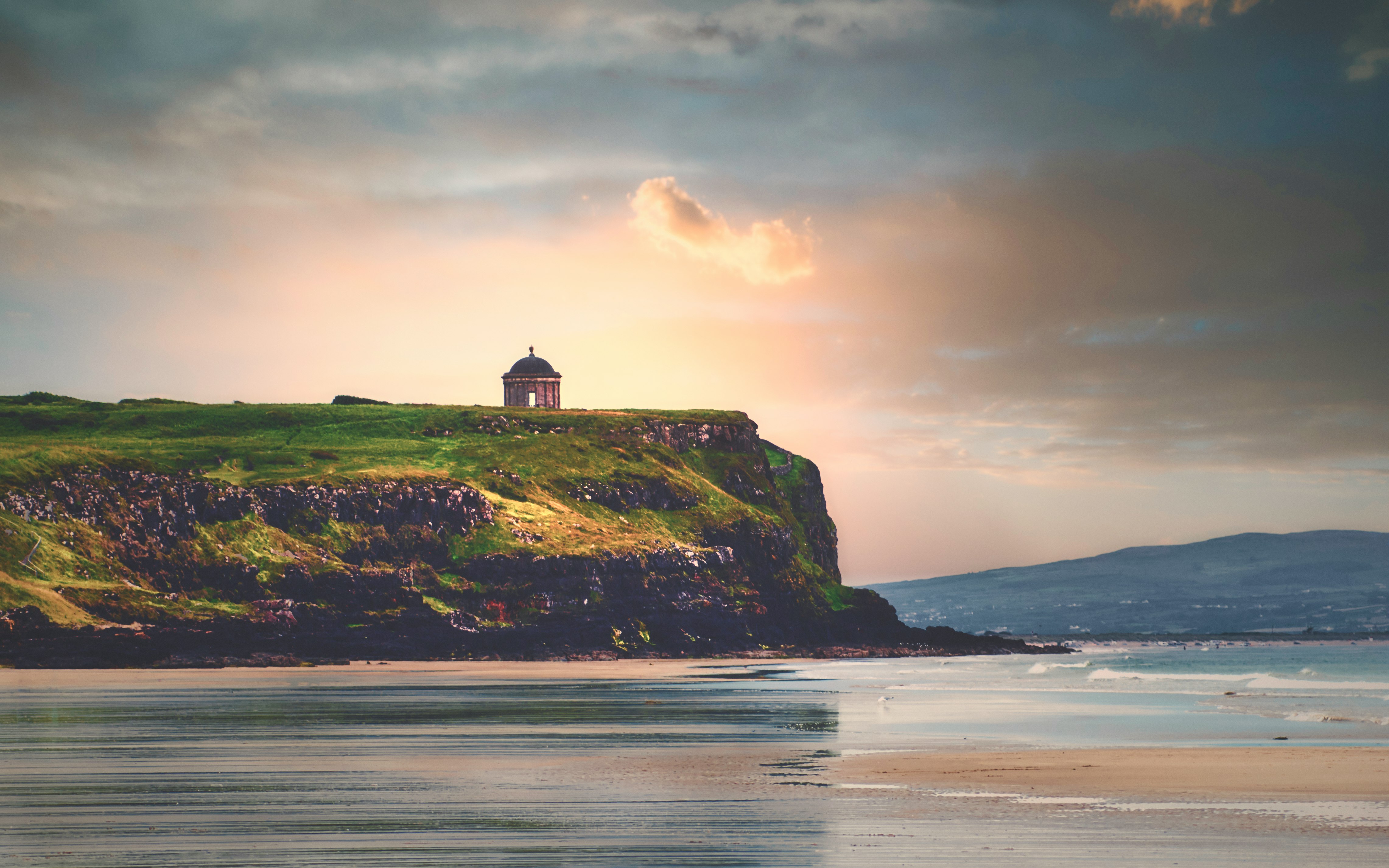 silhouette of lighthouse on hill near body of water during daytime